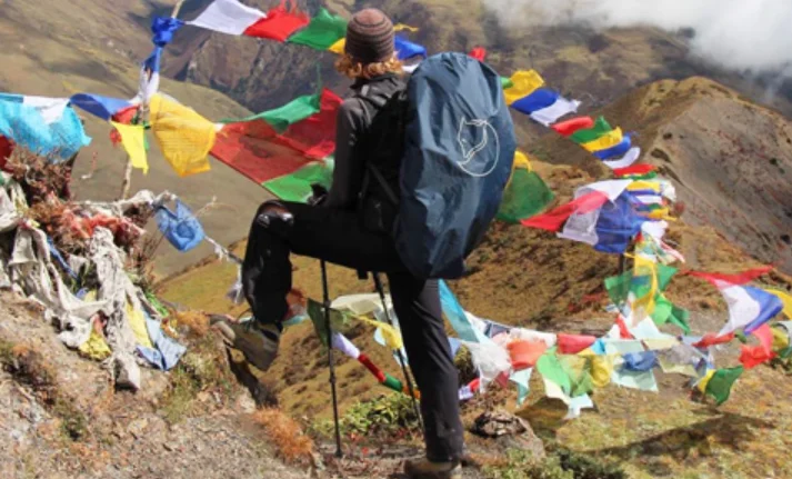 Trekkers crossing a high mountain pass with Himalayan peaks behind them in Bhutan — what to do in Bhutan